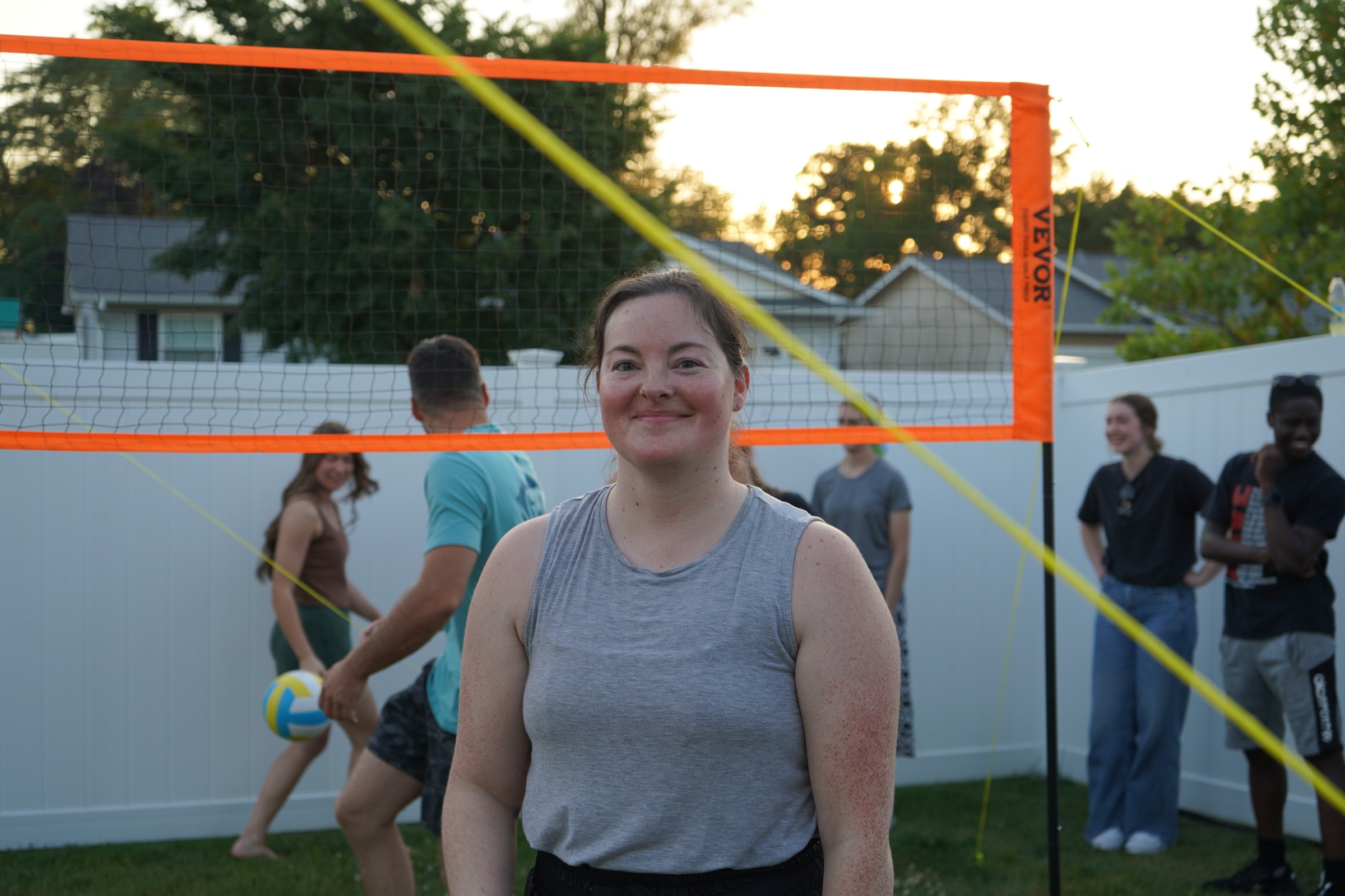 Young woman smiling near a sunset volleyball game at CFC Young Adults