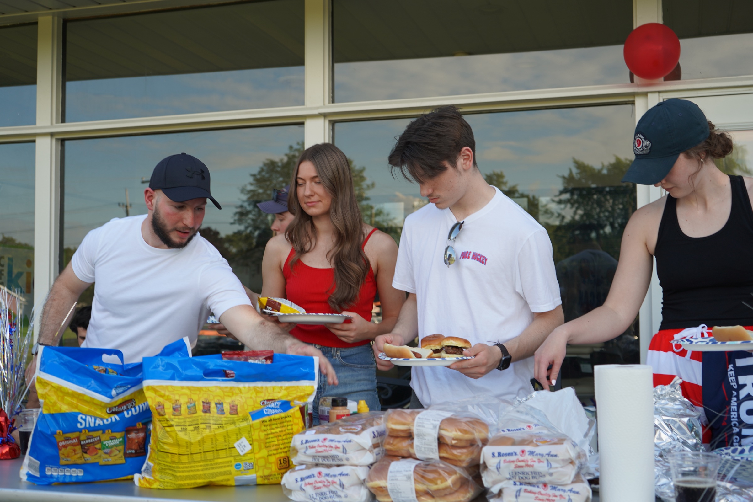 Young adults gathering around a cookout serving table