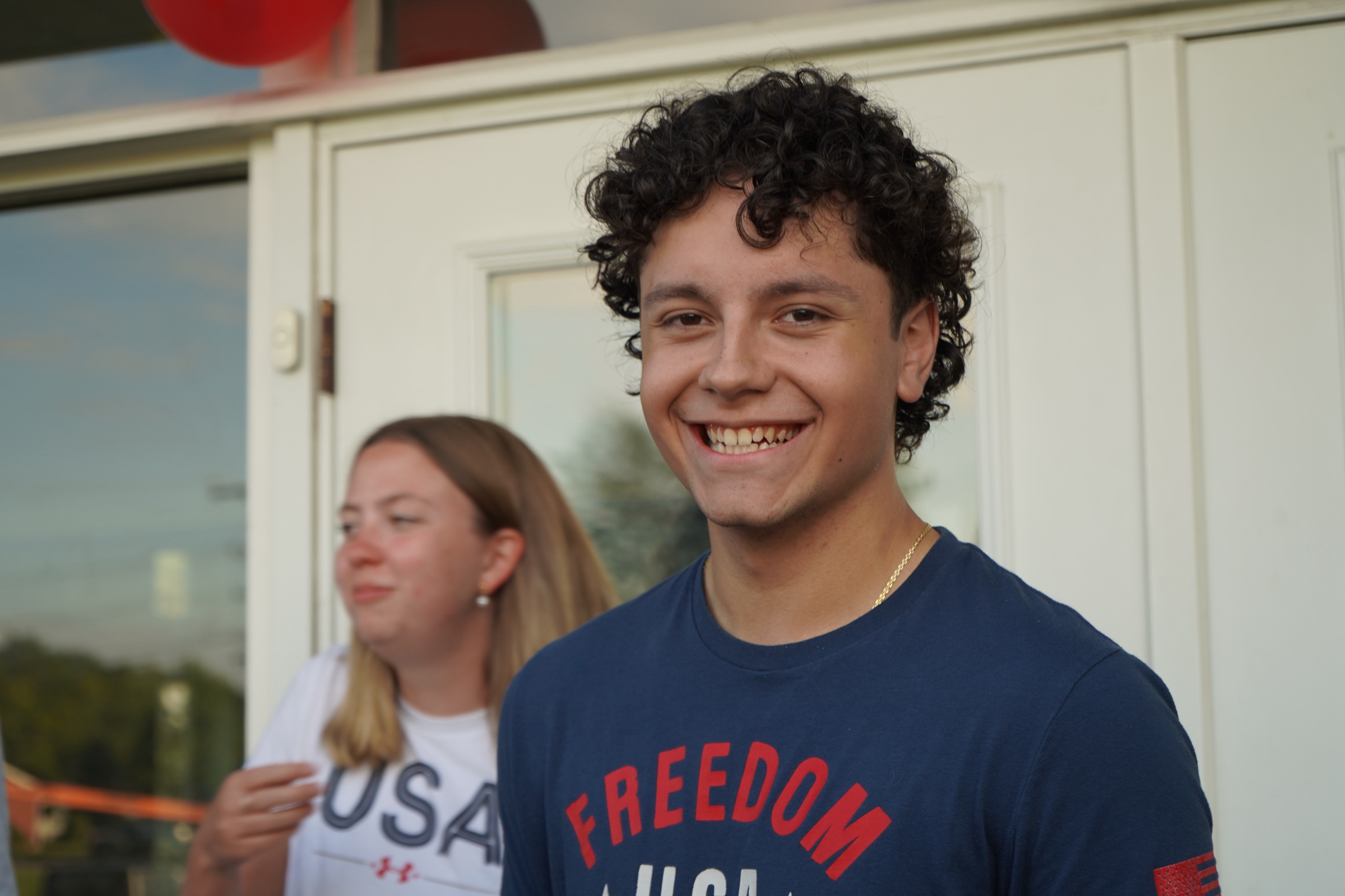 Portrait of a young man with curly hair against red balloons