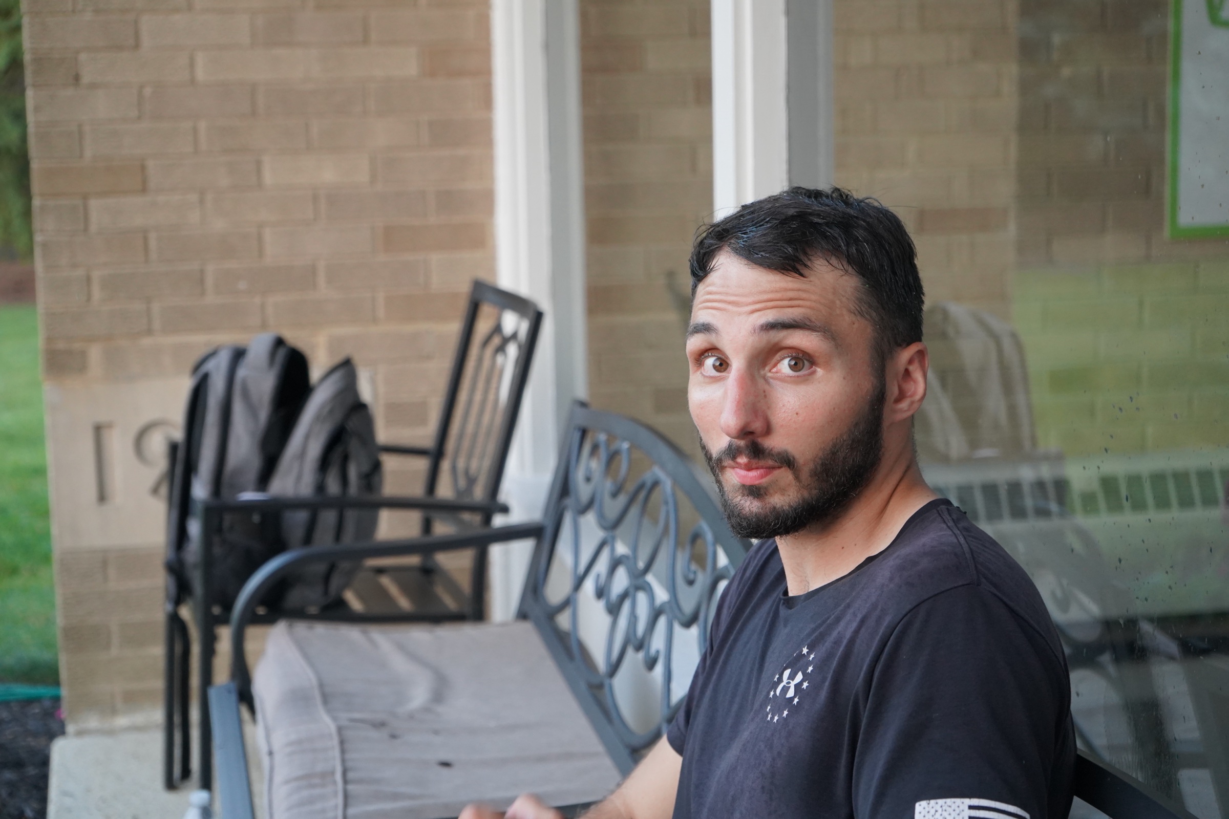 Young man seated on a bench near a brick wall