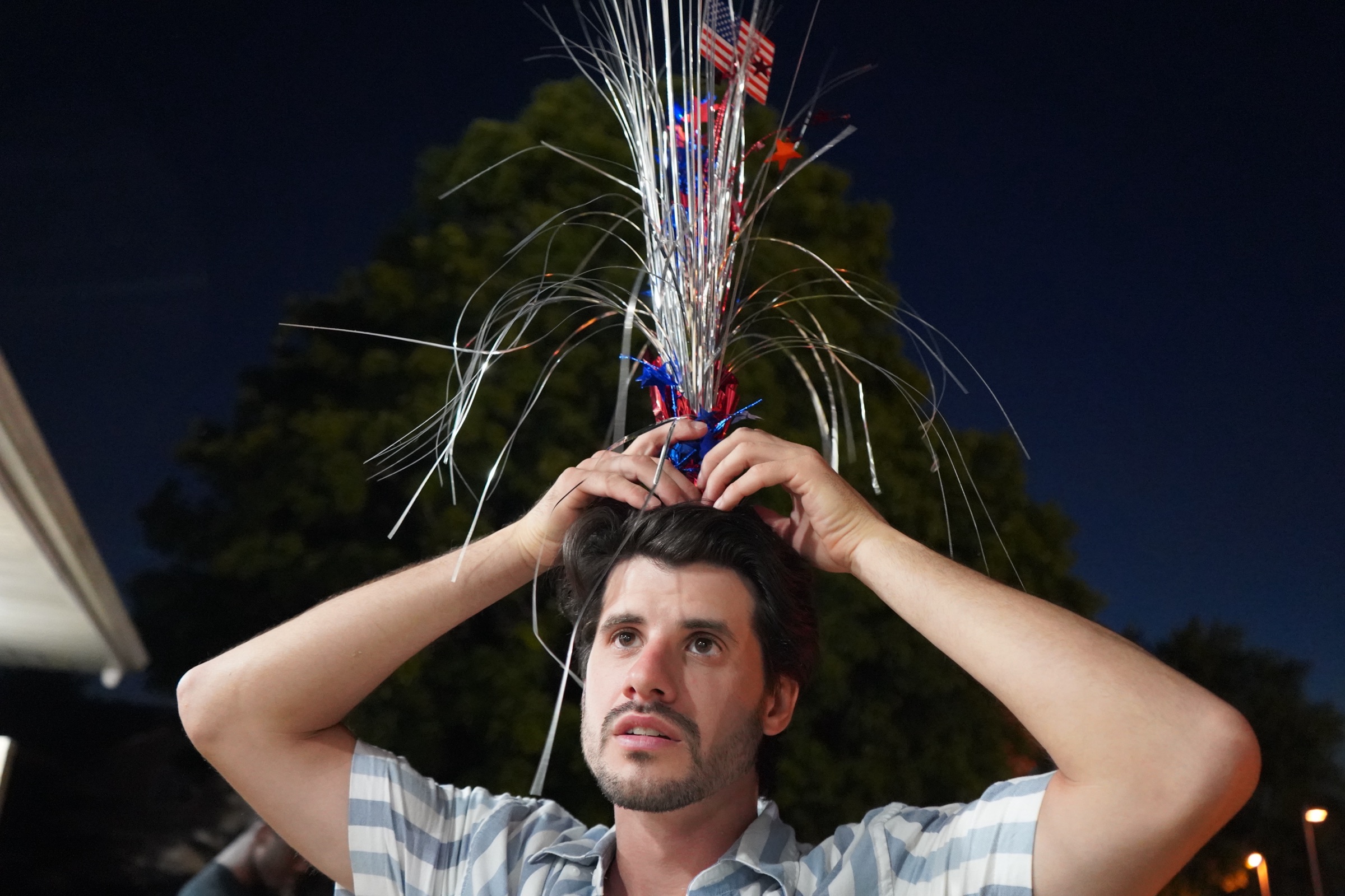 Night photo of a young man holding a centerpiece above his head
